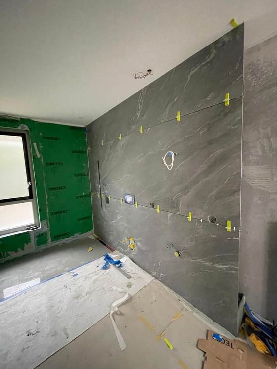 Erste Feinsteinzeug-Platte wird an der Wand ausgerichtet