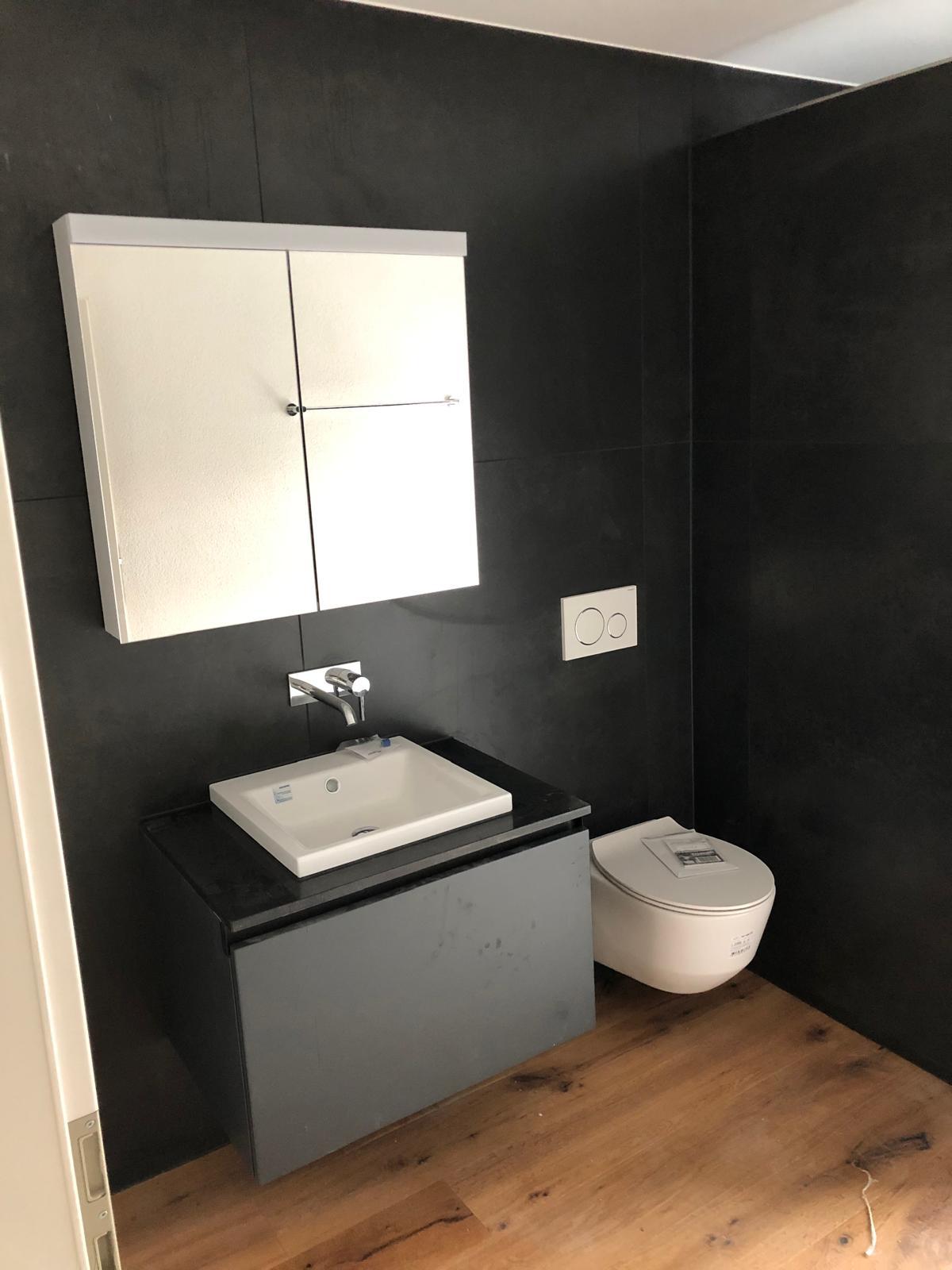 Kompaktes Gäste-WC mit anthrazitfarbenen Grossformatplatten und Spiegelschrank