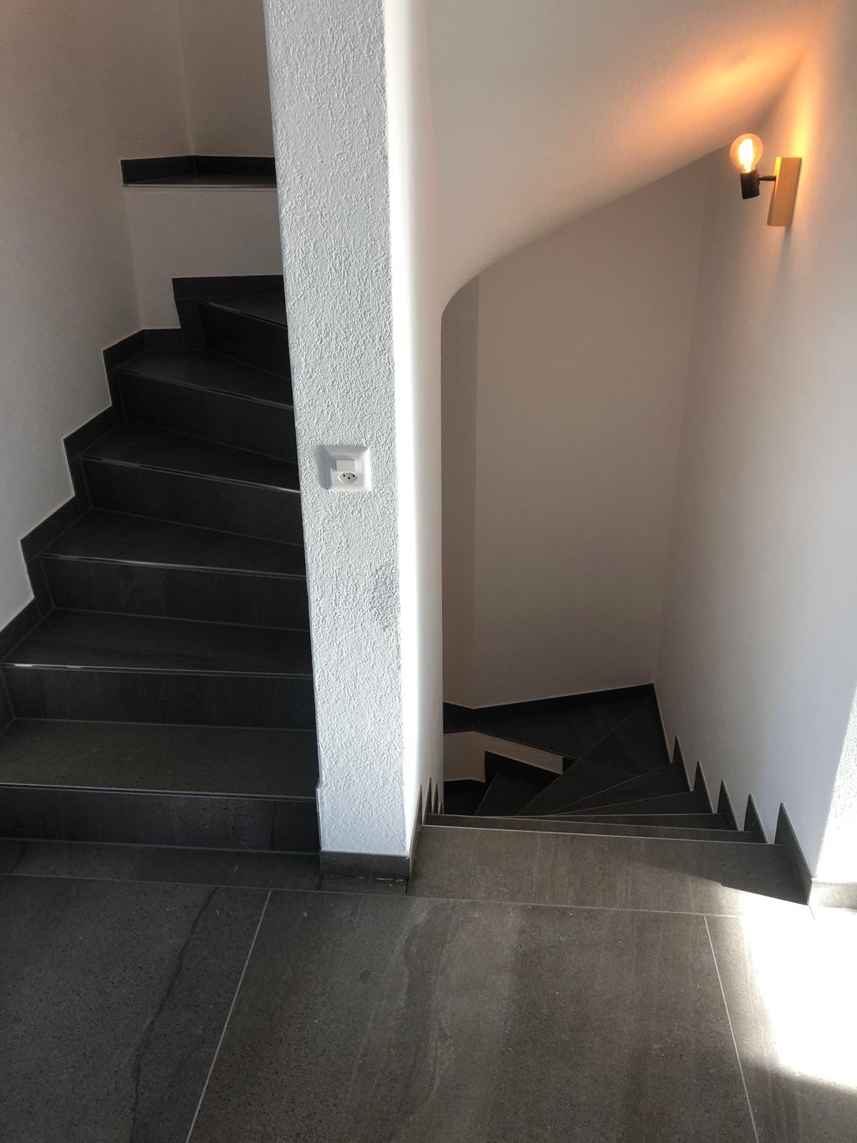 Gewendelte Treppe, durchgehend mit dunklem Feinsteinzeug belegt